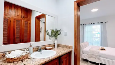 a bathroom with a sink and a mirror and a bed at Pool View, Walk to Beach, Shops, Dining, Fast Wifi in Punta Cana