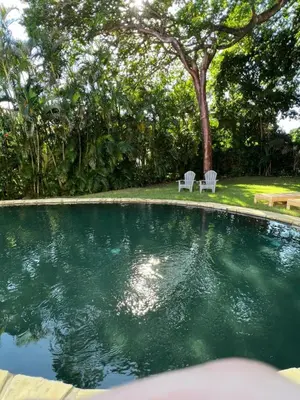 a swimming pool with two white chairs in a yard at Villa Marina in Sosúa