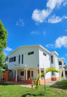 a white house with a palm tree in front of it at Casa Maritza in Las Galeras