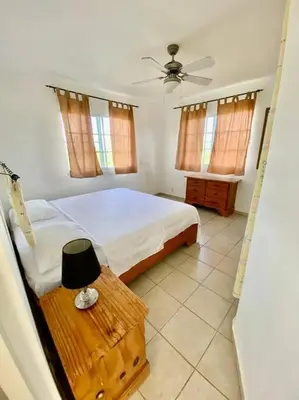 a bedroom with a bed and a table with a fan at Casa Blanca Samaná - Las Galeras in Las Galeras
