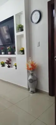 a vase with flowers in a room with a clock at 13 de las Americas in La Alianza
