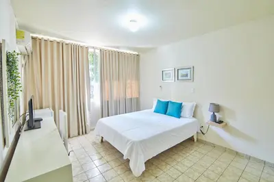a bedroom with a white bed with blue pillows at Modern Santo Domingo Condo in Heart of Gazcue in Santo Domingo