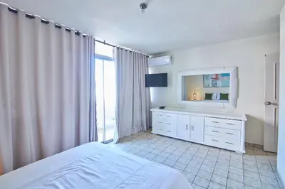 a bedroom with a bed and a dresser with a television at Modern Santo Domingo Condo in Heart of Gazcue in Santo Domingo
