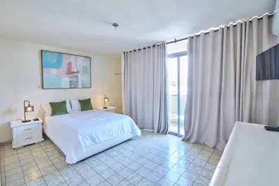 a bedroom with a white bed and a large window at Modern Santo Domingo Condo in Heart of Gazcue in Santo Domingo