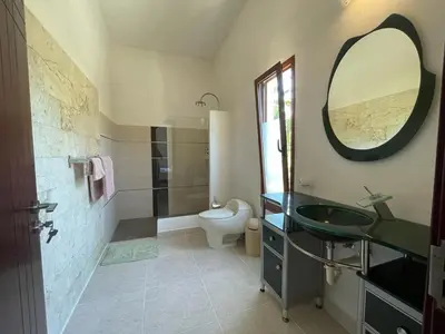 a bathroom with a sink and a toilet and a mirror at Okaina 7 Penthouse in Cabarete