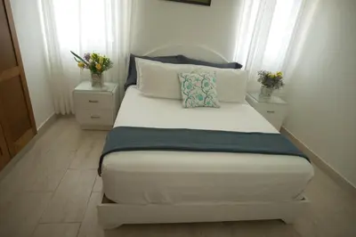 a bedroom with a bed with two night stands and two windows at VillaGuerra-Piscina-Billar-BBQ-WiFi-Cozy-3Br-5Bds-7Pax in Guerra