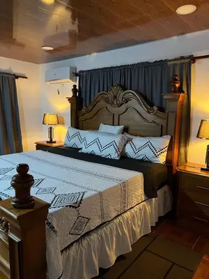 a bedroom with a large bed with a wooden headboard at Villa Jarabacoa in Concepción de La Vega