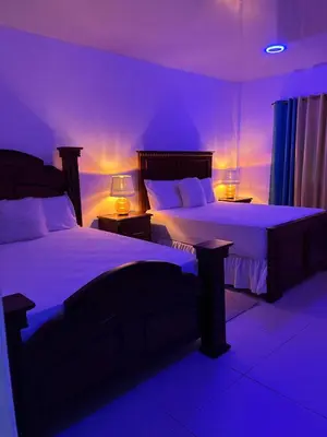 a purple bedroom with two beds and two lamps at Villa Jarabacoa in Concepción de La Vega
