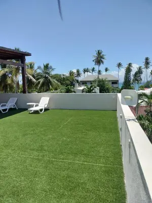 a patio with green grass and two white chairs at Vacacional las pascualas in Sánchez