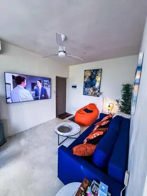a living room with a blue couch and a flat screen tv at Kaleidoscopic Apartment in La Majagua