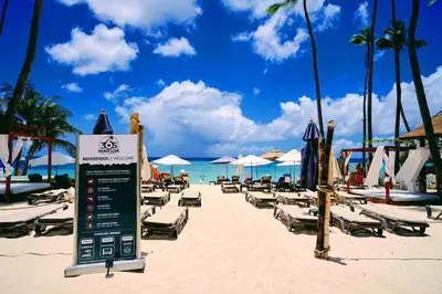 a beach with lounge chairs and a sign on the sand at Rooftop, Pool View, Walk to Beach, Dining, Shops in Punta Cana