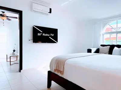 a bedroom with a bed and a flatscreen tv on the wall at Rooftop, Pool View, Walk to Beach, Dining, Shops in Punta Cana