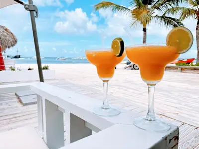 two glasses of orange juice sitting on a bench on the beach at Rooftop, Pool View, Walk to Beach, Dining, Shops in Punta Cana