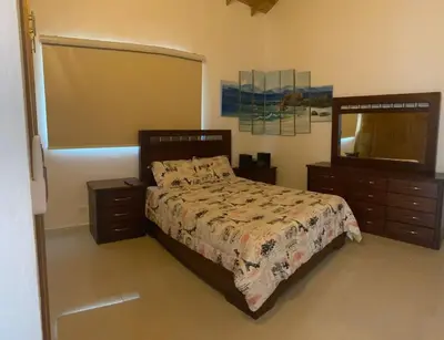 a bedroom with a bed and two dressers and a mirror at casita del padre pio in Punta Rucia