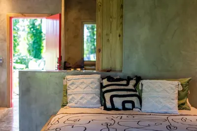 a bedroom with a bed with pillows and a mirror at REFUGIO Nature meets Luxury in Sabaneta de Yásica