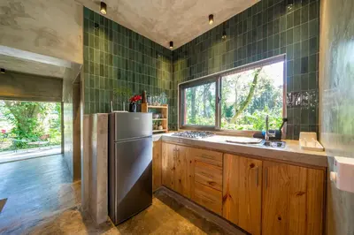 a kitchen with a stainless steel refrigerator and green tiled walls at REFUGIO Nature meets Luxury in Sabaneta de Yásica