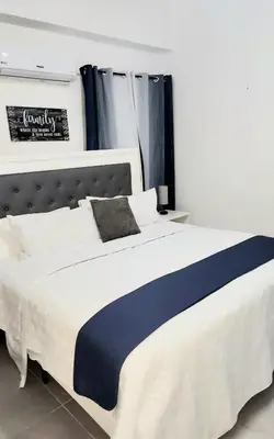 a bedroom with a large white bed with a black headboard at Lindo 1BD apt in Bella Vista with Pool, Rooftop,Gym,Parking in Santo Domingo