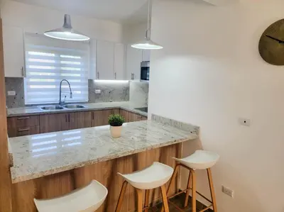 a kitchen with a counter and four stools at Lovely Condo in Gated Community in Sosúa