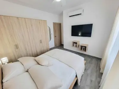 a bedroom with a white bed and a flat screen tv at Lovely Condo in Gated Community in Sosúa
