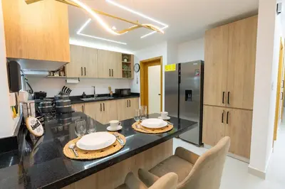 a kitchen with a black counter top and wooden cabinets at Modern 3BR! 9fl, King Bed! Sti!, in Santiago de los Caballeros