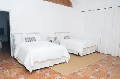 two beds in a white room with white curtains at Cacique 13, Ocean View and Golf Course in La Romana