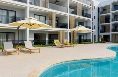 a swimming pool with chairs and umbrellas next to a building at Dream pool views apartment close to the beach in Punta Cana