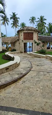 a stone building with palm trees in the background at Confortable vista al mar in Juan Dolio