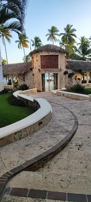 a walkway in front of a building with palm trees at Confortable vista al mar in Juan Dolio