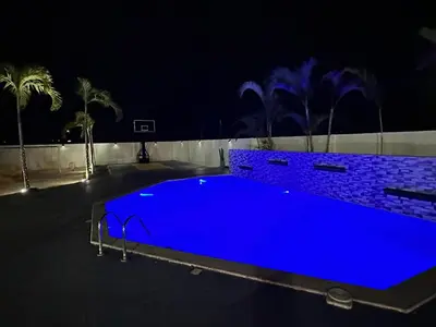 a large blue swimming pool at night with palm trees at Legado Edif V Apto A2 in Azua de Compostela