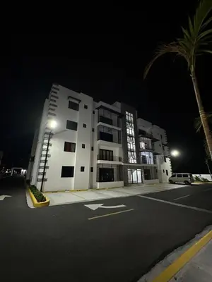 a large white building at night with a palm tree at Legado Edif V Apto A2 in Azua de Compostela