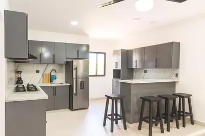 a kitchen with stainless steel appliances and bar stools at 2-bedroom apartment with 24h electricity and private parking in Sosúa