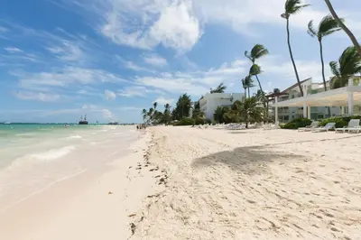a beach with white sand and palm trees and the ocean at Backyard, Pool View, Walk to Beach, Dining, Shops in Punta Cana