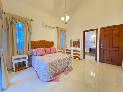 a bedroom with a bed with pink pillows and a door at Beautiful Villa with Mountain view in San Felipe de Puerto Plata