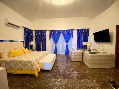 a bedroom with a bed and a tv and blue curtains at Beautiful Villa with Mountain view in San Felipe de Puerto Plata