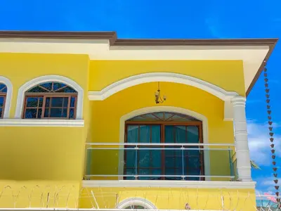 a yellow house with two windows and a balcony at Beautiful Villa with Mountain view in San Felipe de Puerto Plata