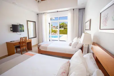 a hotel room with two beds and a desk and a television at Santa Fe Club in Sosúa