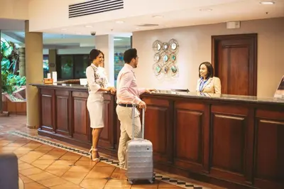 a man and a woman standing at a reception desk at Hodelpa Garden Suites - All Inclusive in Juan Dolio