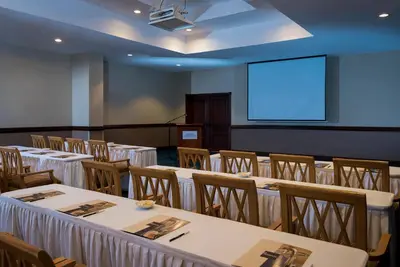 a conference room with tables and chairs and a screen at Hodelpa Garden Suites - All Inclusive in Juan Dolio