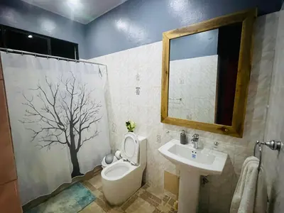 a bathroom with a toilet and a sink with a tree on the wall at Casa en río san Juan 4 habitaciones in Río San Juan