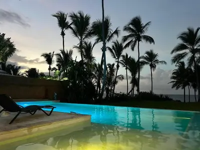 a chair sitting next to a swimming pool with palm trees at Casa Juan Lucas in Las Galeras