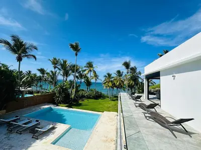 a swimming pool with chaise lounge chairs and the ocean at Casa Juan Lucas in Las Galeras