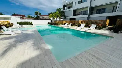 a swimming pool with white chairs and a building at Punta Popy Beach Apartment in Las Terrenas