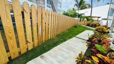 a wooden fence in front of a yard with flowers at Punta Popy Beach Apartment in Las Terrenas