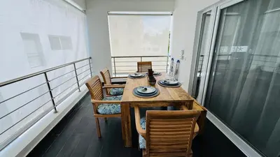 a wooden table and chairs on a balcony with a table at Punta Popy Beach Apartment in Las Terrenas