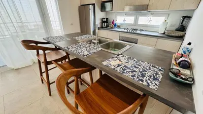 a kitchen with a counter with a sink and some chairs at Punta Popy Beach Apartment in Las Terrenas