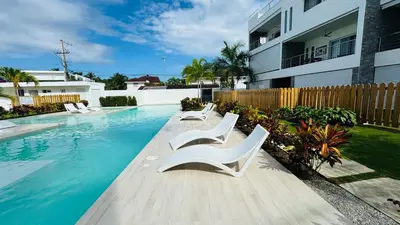 a swimming pool with two white chairs and a house at Punta Popy Beach Apartment in Las Terrenas