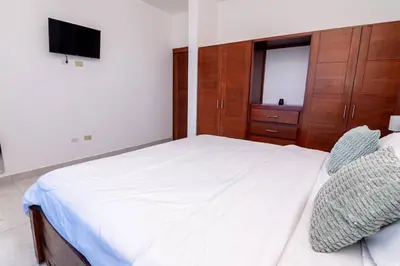 a bedroom with a white bed and a television at Beautiful ocean and mountain view villa in Gaspar Hernández