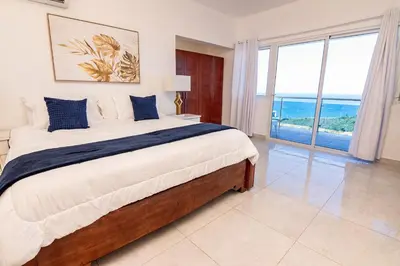 a bedroom with a bed with a view of the ocean at Beautiful ocean and mountain view villa in Gaspar Hernández