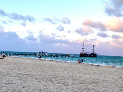 a group of people on a beach with a boat in the water at Central in Punta Cana Beach Life RD in Punta Cana