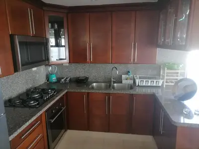 a kitchen with wooden cabinets and a sink and a stove at Quiet apartment, good access to Supermarkets, Center etc in Santo Domingo